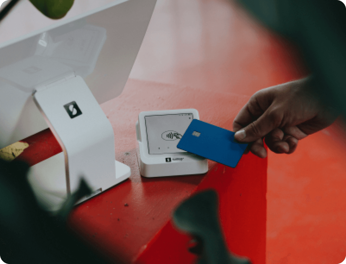 A hand tapping a payment card on a reader